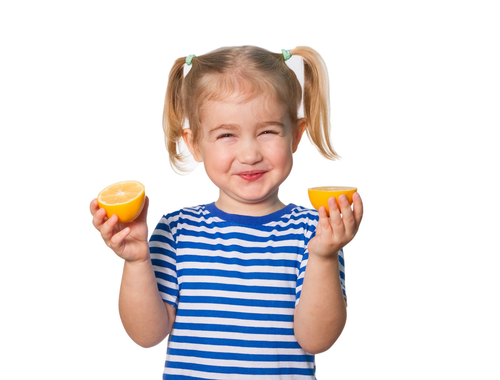 Small girl with pigtails holding a lemon cut in two